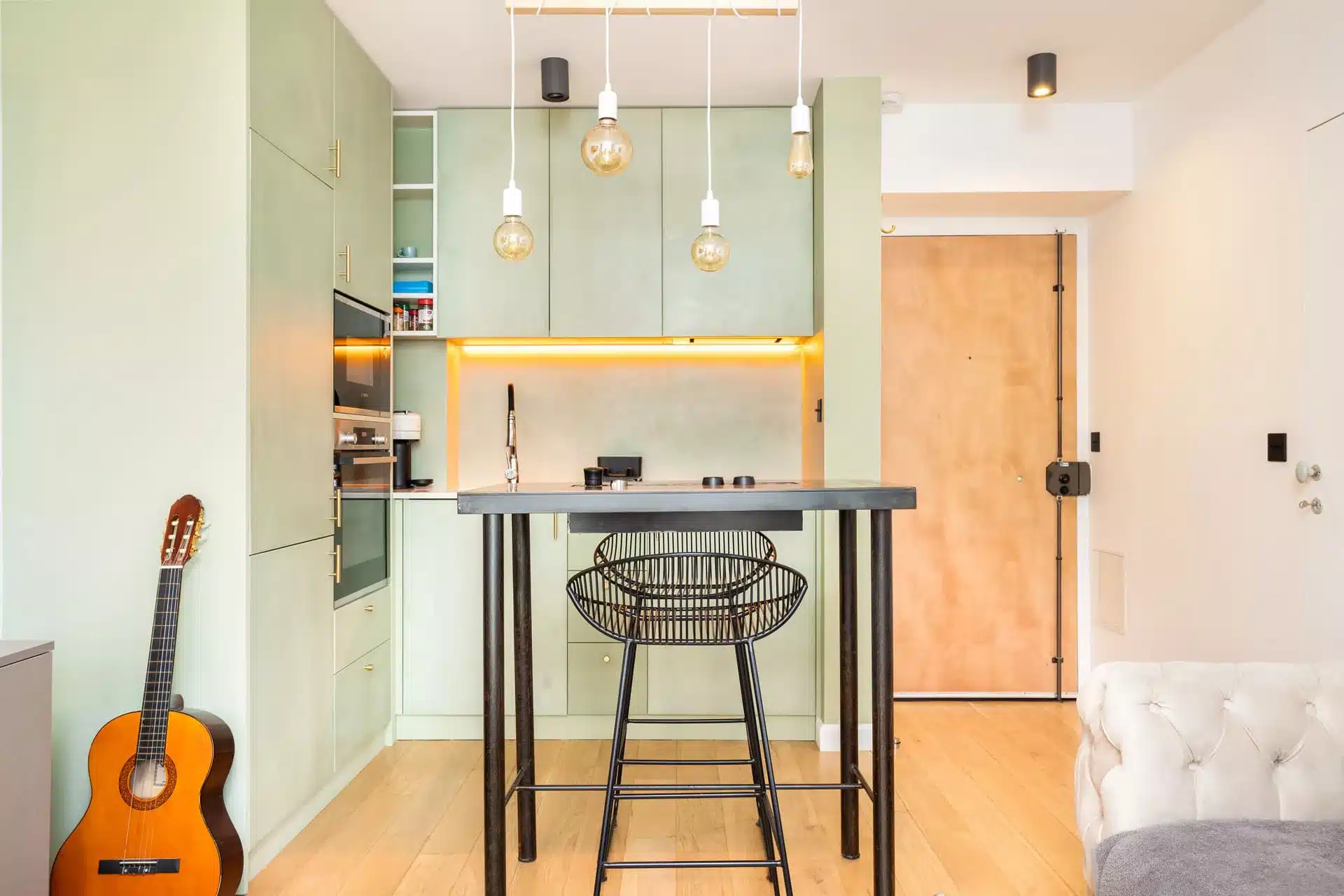 Photographie immobilière professionnelle - cuisine ouverte vert céladon avec îlot bar et suspensions vintage à Clamart 92140