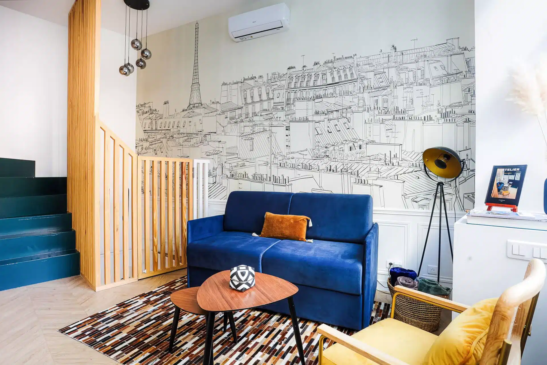 Shooting photo Airbnb Paris 18 - salon duplex avec fresque Tour Eiffel, canapé velours bleu et escalier bois, Montmartre